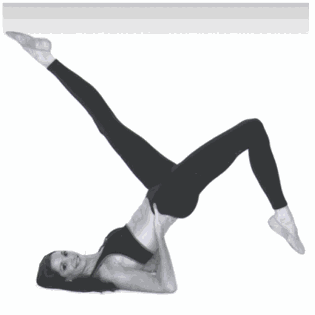 Woman performing advanced Pilates exercise on spine corrector mat in black workout attire