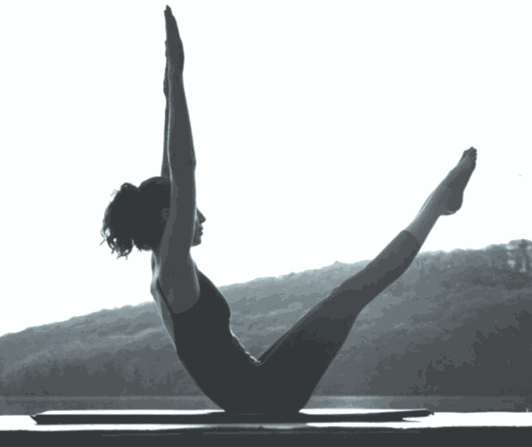 Woman performing intermediate Pilates reformer exercise with arms raised in outdoor setting for Upper-Hand Intermediate Reformer Workshop